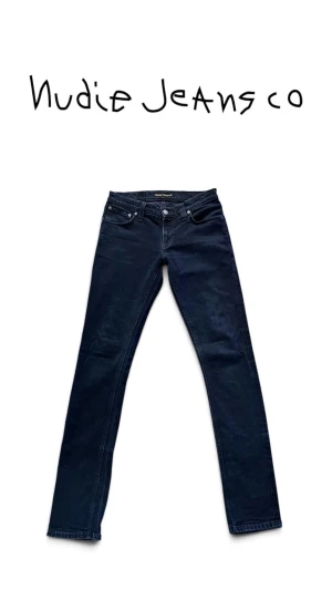Nudie Jeans - Snygga Nudie Jeans Tight Long John i en mörkblå/nästan svart denim. En stilren och tajt modell med en slim, figurnära passform som smalnar av hela vägen ner mot ankeln.  Perfekta jeans om du gillar en clean och mer fitted look. Den mörka färgen gör dem dessutom väldigt enkla att matcha med sneakers, hoodie eller t-shirt.  • Märke: Nudie Jeans Co • Modell: Tight Long John • Storlek: W28 L34 • Färg: Mörkblå • Passform: Slim fit • Skick: Mycket fint skick  📦 Skickas välpackade 💬 PM vid frågor