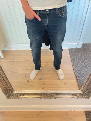 Mörkblå Levis slim fit jeans  - Säljer ett par mörkblå slim fit jeans med snygga slitningar på låren. Modellen är 183. Storlek 30/32. Hör av er vid funderingar!