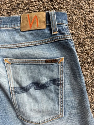 Nudie jeans Grim Tim  - Säljer ett par selvage jeans från Nudie Jeans med slitningar och riktigt fin ljus tvätt. Jeansen har en slim/ rak passform och tydliga slitningar. Storleken är 31W 32L. Säljes då de tyvärr är för små för mig. Hör av er vid frågor eller funderingar!