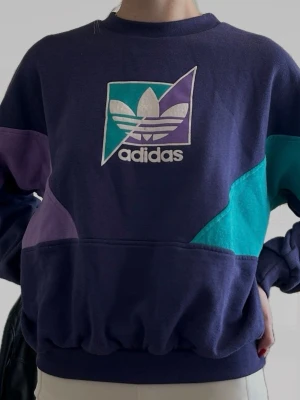 Retro adidas-tröja - Retro långärmad Adidas-tröja i lila och turkos. Lös passform på mig som brukar ha storlek S. Köpt på Humana i Stockholm