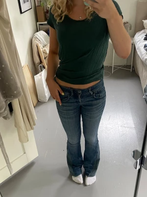 Blå bootcut jeans med låg midja - Säljer ett par blå bootcut jeans med låg midja. Jeansen är omgjorda från skinny till bootcut med lim som ska hålla tvätt. Tyvärr har det blivit ett litet hål på ena benet baksida dock inget man tänker på vid användning (se bilder). Materialet är stretchigt och skönt. 