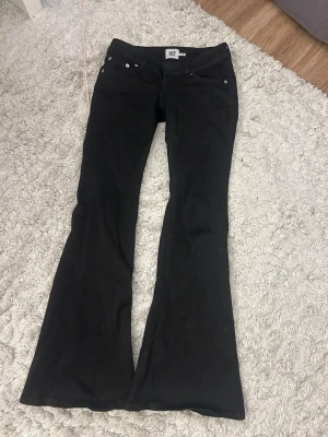 Svarta bootcut low waist jeans från 157 - Säljer ett par svarta bootcut jeans från 157 i storlek XS. Jeansen har klassisk femficksdesign, utsvängda ben och är tillverkade i stretchigt material för skön passform. Perfekta till sneakers eller boots för en trendig look.