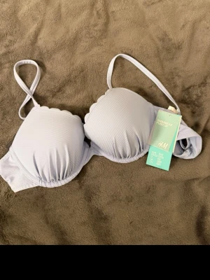 Ljuslila bikiniöverdel - Supersöt ljuslila bikiniöverdel från H&M med vadderade kupor och scallop-detaljer längs kanterna. Justerbara axelband och klassisk knäppning bak. Perfekt för strandhäng eller poolparty.
