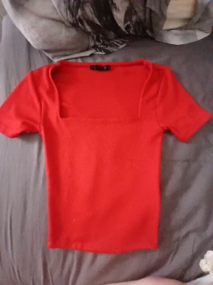 Röd topp med fyrkantig urringning Amisu - Snygg röd topp från Amisu med fyrkantig urringning och korta ärmar. Toppens material känns mjukt och stretchigt, perfekt för att lyfta vilken outfit som helst. Enkel men ändå trendig design som passar till mycket.