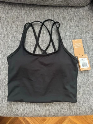 Aim'n Svart sport-bh  - Snygg svart sport-bh med tunna korsade axelband i ryggen. Tillverkad i ett stretchigt och mjukt material som passar perfekt för träning eller yoga. Enkel och stilren design utan synliga loggor eller mönster.