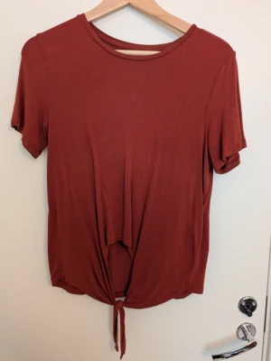 Roströd t-shirt - Säljer en enkel och snygg roströd t-shirt med knyt från Pieces i storlek XS
