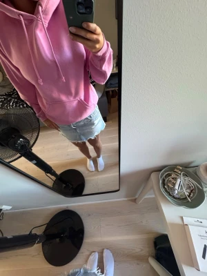 Rosa hoodie med huva - Säljer en snygg rosa hoodie med huva och dragsko. Hoodien har en klassisk passform, ribbade muddar vid ärmslut och nederkant samt en känguruficka framtill. Perfekt för en chill och avslappnad stil.