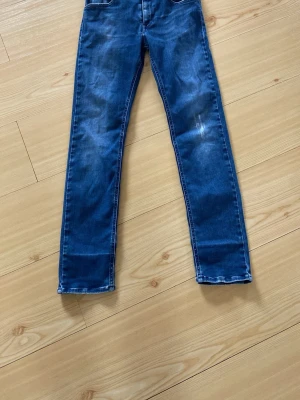 Blå raka jeans med vit söm - Snygga blå jeans med raka ben och kontrasterande vita sömmar. Klassisk femficksmodell i stretchigt denimtyg som sitter skönt och passar till det mesta. Perfekta för dig som gillar en enkel och stilren look.
