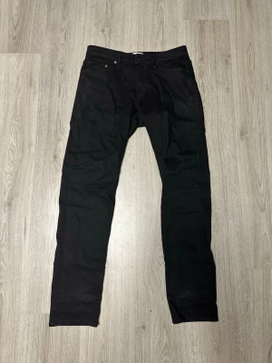 Svarta raka jeans stretch material  - Svarta jeans med rak passform och klassisk femficksdesign. Jeansen har normal midja och är tillverkade i ett mjukt denimtyg som ger en clean look. Perfekta för dig som gillar en stilren och enkel stil.