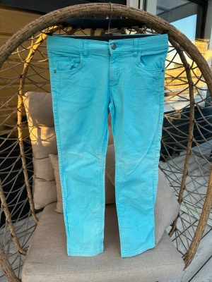 Jeans för flickor - Snygga turkosa jeans från KappAhl med klassisk femficksmodell och knappgylf. Byxorna har smal passform och är tillverkade i ett mjukt bomullstyg med lite stretch.