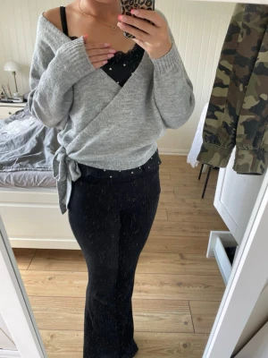 Grå omlottstickad tröja med knyt - Säljer en grå omlottstickad tröja med knyt i sidan. Tröjan är ifrån even&odd i storlek M.
