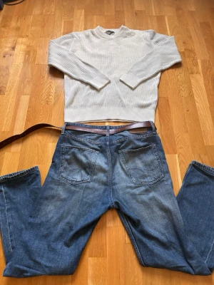 Vit ribbstickad tröja  - Vit ribbstickad tröja från med rund hals och långa ärmar. Tröjan har breda muddar vid ärmslut och nederkant, och är gjord i ett mjukt material som ger en clean och stilren look.