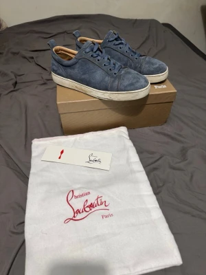 Blå mockasneakers från Christian Louboutin - Snygga blå sneakers i mocka från Christian Louboutin med vita sulor och matchande blå skosnören. Skorna har en klassisk låg profil och beige innerfoder för extra komfort. Perfekta för dig som vill ha en stilren och exklusiv look.