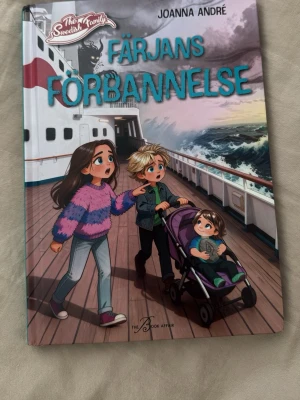Färjans förbannelse av Joanna André - En spännande bok med färgstarkt illustrerat omslag där tre barn är på ett fartyg i stormigt väder. Boken handlar om syskonen Alma och Harry som hamnar i ett mystiskt äventyr på en färja till Åland. Perfekt för dig som gillar mysterier och familjeäventyr.