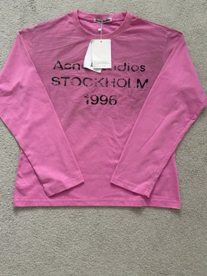 Rosa långärmad  Acne Studios - Säljer en rosa långärmad topp från Acne Studios med tryck i svart text 'STOCKHOLM 1996' på bröstet. Passar dig som är 165-175. Priset går att diskutera.