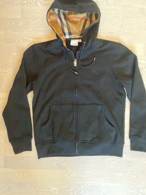 Svart burberry hoodie - Tja! Säljer en helt ny Snygg svart zip hoodie från Burberry.                                                                                  Storlek är medium/small och måtten finns på sista bilderna.                                                                                   Den är helt ny så aldrig använd bara testad.                     Priset kan diskuteras och skickar inom 24 Tim ☺️💨