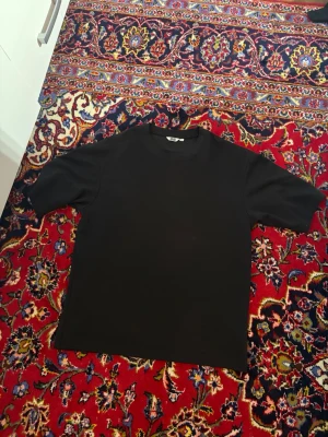 Uniqlo AIRISM T-shirt - En enkel svart t-shirt med rund hals och korta ärmar. Tillverkad i mjuk bomull och har en klassisk passform som funkar till det mesta. Perfekt basplagg för garderoben.