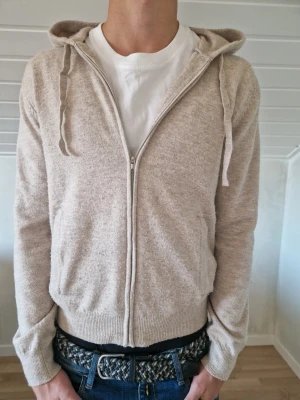 Cashmere zip up - Beige cashmere zip up hoodie. Storlek är 164 cm men den är mycket större egentligen. Killen på bilden är 175 så skulle säga att den sitter som bäst på dig om du är mellan 170-175 cm