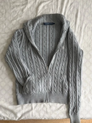 Grå kabelstickad ziptröja Polo Ralph Lauren - Kabelstickad grå tröja med dragkedja från Polo Ralph Lauren. Tröjan har hög krage, långa ärmar och ribbade muddar samt nederkant. Ska vara ärlig den har krympt, påverkar inte materialet eller proportionerna, Jag gillade tröjan men sitter mer som en XS/S nu. Kan skicka mått som så önskas