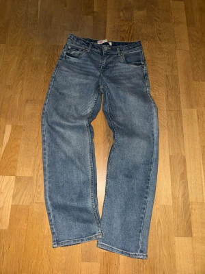 Blå raka jeans från Levi's - Klassiska blå jeans från Levi's med rak passform och fem fickor. Jeansen har en ljus tvätt och är tillverkade i bomull. Perfekta för en avslappnad och tidlös stil.