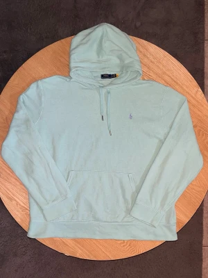 Polo Ralph Lauren Hoodie Mintgrön – Storlek XXL - Säljer en Polo Ralph Lauren hoodie i fin mintgrön färg.  Klassisk modell med broderad polo-logga på bröstet, huva med snören och kängurificka.  Storlek: XXL  Skick: Fint skick, inga defekter. Tvättad och klar.  Unisex.  Mått kan tas vid förfrågan.