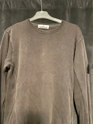 sweatshirt Stone Island - Säljer en grå sweatshirt från Stone Island med klassisk rund halsringning och ikonisk patch på vänster ärm. Tröjan har en avslappnad passform och är tillverkad i mjukt bomullsmaterial. Perfekt för dig som gillar streetwear och stilrena plagg.