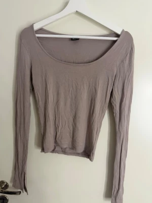 Ljusbeige långärmad topp - En enkel och stilren ljusbeige långärmad topp med rund halsringning. Tillverkad i mjukt material som känns skönt mot huden. Ärmarna har en liten slitsdetalj vid ärmsluten för en extra touch.