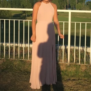 Balklänning STL: S - Superfin balklänning från Nelly med öppen rygg. Den försluts med dragkedja på ryggen och har spetsdetaljer. Det är ett band som markerar midjan på ett snyggt sätt. Färgen är ljusrosa, det syns bäst på bilderna där klänningen är på. Nypris: 800kr.                                                                                Köparen står för frakt