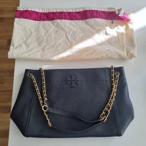Väska Tory Burch  - Svart väska I läder med guld detaljer. Storlek mellan. Väskan är lite mer än 2 år finns kvitto. Den är i väldigt fint skick då den ej användts så mycket.