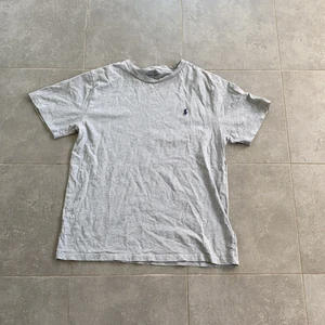 En grå T-shirt från kidsbrandstore - En grå T-shirt från kidsbrandstore, märke Polo Ralph Lauren, nästan helt oanvänd. 