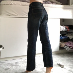 Mörkblå raka jeans - Mörkblå jeans med gula sömmar från lee köpta här på Plick. De är insydda i midjan för att passa ungefär w26. Går ner till fötterna på mig som är 170. Fint skick. Skriv till mig för fler bilder eller frågor😊 köpare står för frakt