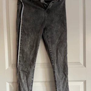 Skinny low rise jeans i srl 38  - Skinny low rise jeans från berskha. Fin grå färg med svart och vit/grå rand på båda sidorna. Skulle säga att formen är normala och inte låga i midjan! Väldig töjbara jeans så formar sig fint! 