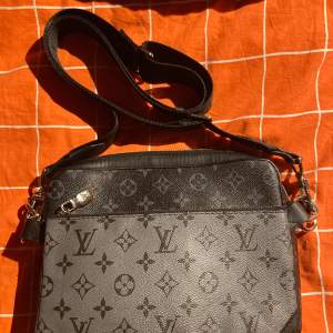 Lui Vuitton väska i tre delar som man kan plocka isär. En stor svart del som är helt svart, en lite mindre del som kan vara både svart och vit, tillsisst en korthållare som får plats med de vettiga. Väskan är lätt att matcha med eftersom den är svart funkar till presic alla stilar, både tjejer och killar kan bära plagget !! 