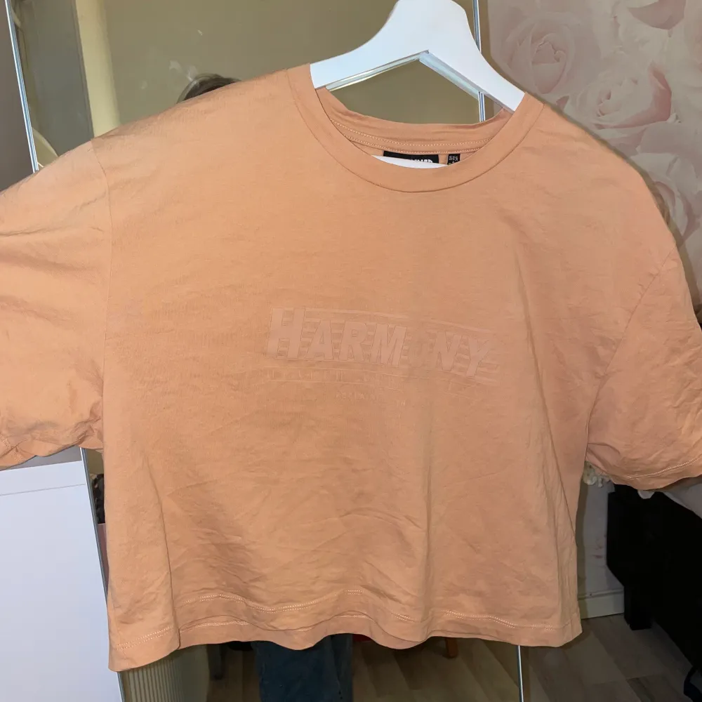 En lite croppad orange t-shirt med ett mörkt ”Harmony”-tryck! Superskön att ha på sig, tunnt tyg som andas bra! Använd 1-3 gånger🧡 . T-shirts.