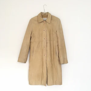 Beige skinnkappa - Jättefin beige skinnkappa som säljes då den ej kommer till så stor användning. Storlek 42 men funkar på mig som vanligtvis har strl 38 då jag tycker om när det är lite oversized. Slutar precis nedanför knäna på mig som är 164 cm. Köparen står för eventuell fraktkostnad och betalning sker helst via swish.