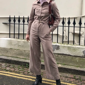 Beige byxdress strl 40  - Supersnygg beige byxdress i storlek 40, i fint begagnat skick. Skärpet finns dock inte kvar, jag har föredragit att använda den med ett skinnskärp istället. Jag är en 38a vanligtvis, denna sitter perfekt på mig förutom att den är kort i benen på mig som är 180 lång.