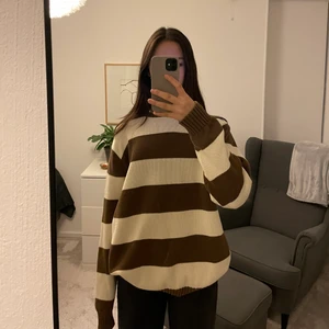 Brandy Melville brun/vit stickad tröja - Hoodien är nästan ny alltså i väldigt bra skick. Hoodien är stickad och är väldigt bekväm. Den har brun och vita ränder och har en fin, brun hals och arm mudd. Jag är 170 cm och hoodien är lång med långa ärmar. Nypris 350kr.