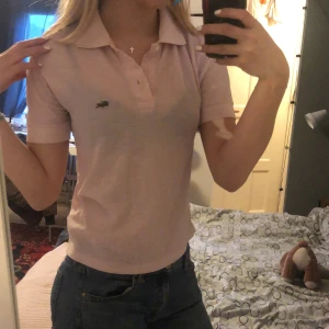 Lacoste - Supersnygg ljusrosa Lacoste piké! Denna är så himla fin men tyvärr för liten för mig, köpte för ca 900kr men säljer för 250kr då den är lite sliten men inget som syns på utsidan. (Pris kan diskuteras)