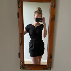 Klänning  - En kortare klänning med knytning i midjan. Snygga detaljer framtill och guldig kedja. Köpt från spanien. Frakt tilkommer 