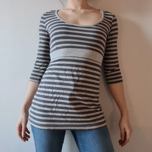 Grå randig långärmad topp med knytband - Grå, randig, topp med knytband i ryggen (går att knyta framtill om så önskas) och trekvartsärmar. Skönt material.