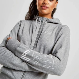 EA7 Zip Hoodie  - Riktigt snygg hoodie som är köpt på JD för 2 år sedan. Den har ett pyttelitet märke utav blekning men det är inte något som syns och den vita texten har ändrat lite färg pga tvätt. I använd skick. Köptes för 1200kr