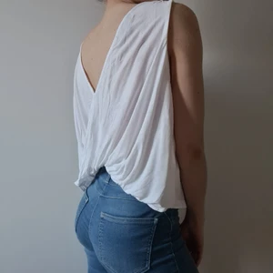 Vit topp med v-ringning i ryggen - Vitt topp, linne, med v-ringning och omlottfall i ryggen.