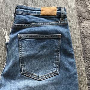 Jeans från GinaTricot. - Blåa jeans från GinaTricot. Utsvängda ben med ankel längd. Fransade vid benslutet. Storlek 38. Hög midja. Knappt använda. Katt finns i hemmet.