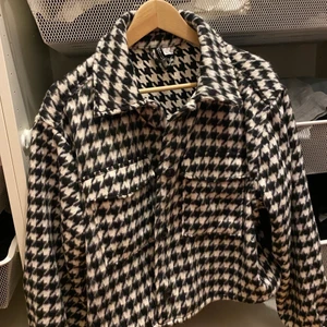 Hundtandsmönstrad kort jacka  - Hundtandsmönstrad kort jacka från H&M. Strl L men skulle säga att den passar från M beroende hur man vill att den ska sitta. 