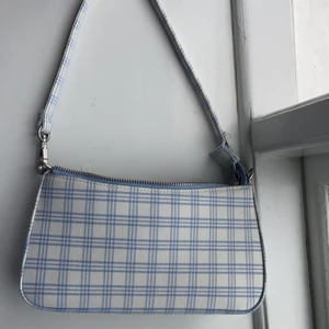 Blå rutig väska  - Säljer min jättefina blårutiga axelväska från brandy Melville❤️ bra sick endast andvänd fåtal gånger💗 väskan har ett fack där back och ett innerfack och nu typ innerfickor💞