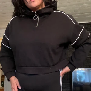 Svart cropped hoodie med dragkedja - Svart hoodie med liten dragkedja samt vita streck. Köpt på h&m för något år sedan, relativt mkt använd men fortfarande i gott skick. 💌 Frakt är baserad på frimärken. Önskas postnords påsar/kartonger går det att ordna