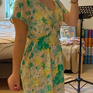 Blommig klänning - Blommig klänning från forever21 med midjeband som man knyter där bak. Pärlor vid bysten. Aldrig använd och är i väldigt fint skick! Storlek M. OBS frakten ingår INTE i priset :)