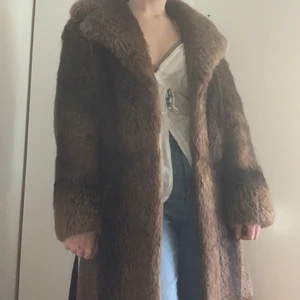 Pälsjacka. Lång äkta  - Detta är min älskade långa pälsjacka. Den är lite för stor för mig tyvärr har verkligen försökt få den att passa. Den är jätte fin brun med ett skinnsnöre att knyta om perfekt värme till vintern. Den enda som är sönder är innearmens tyg som har en söm som gått upp detta är inget man märker när man har på sig den och kan lagas lätt själv hemma. Jag tror jag kan laga de innan ja säljer den men annars olagad för ett billigare pris 