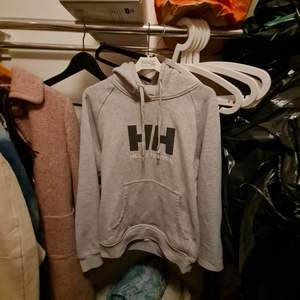 Här har vi en hoodie i grå där det står med märka bokstäver Helly Hansson. Den äkta och använd men inga hål och skavanker.