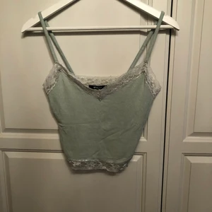 Linne från Gina Tricot  - Linne från Gina Tricot. Jätte fin mintgrön färg som inte riktigt vill komma fram på bild.   Använd ytterst få gånger då banden är lite för långa för mig och jag har varit för lat för att sy in de och nu är linnet inte riktigt mig stil.   Ribbat som syns på bild 2, med spets både upptill och nedtill. Super fint nu till sommarn till ex ett par vita jeans eller något!   Strl: S, sitter tajt och fint på mig.   Undrar du något kolla profilen eller kika in i chatten ☺️